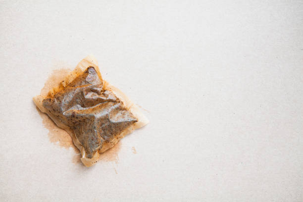 A single used teabag of black tea in the corner of a textured background