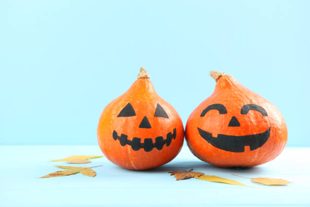 istock pumpkins with painted faces on a colored background for Halloween. 1281652000
