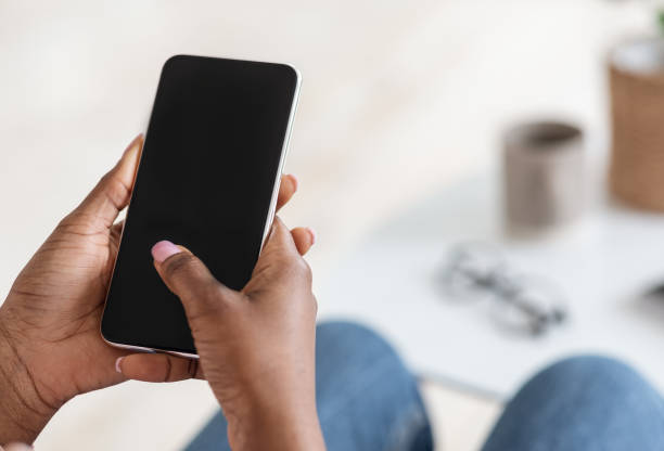 Unrecognizable Black Woman Using Smartphone With Blank Black Screen At Home