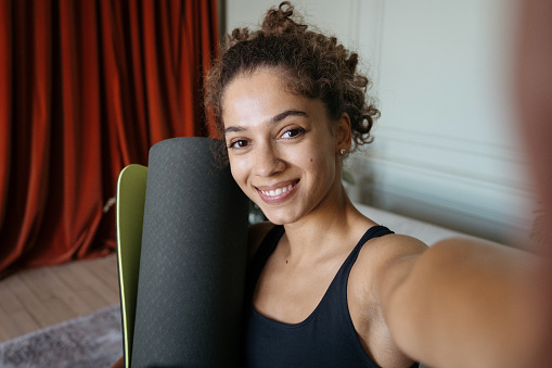 Face portrait of happy adult african american sporty woman taking self photo on camera after training and sport exercise at home. Smiling girl making online video call