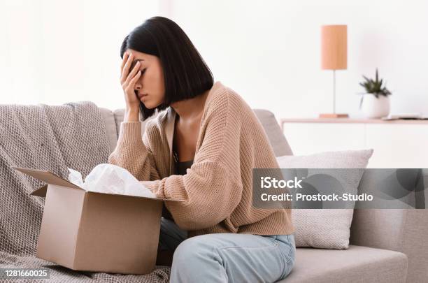 Sad Young Lady Unpacking Wrong Parcel Delivery Mistake Stock Photo - Download Image Now