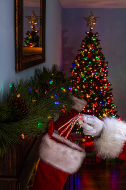 istock Santa Claus placing 3 candy canes into a stocking hanging on a fireplace mantel 1281660185