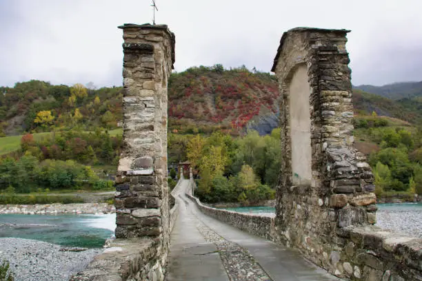 hunchback medieval irregular bridge on trebbia river in Bobbio, Italy