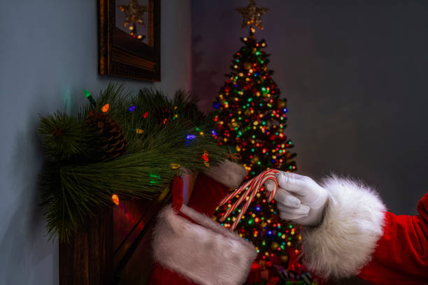istock Santa Claus placing 3 candy canes into a stocking hanging on a fireplace mantel 1281661246