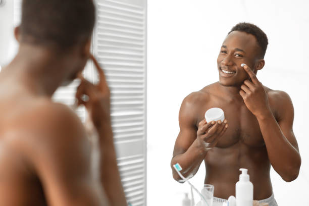 istock Black Guy Applying Cream On Face Standing Shirtless In Bathroom 1281661292