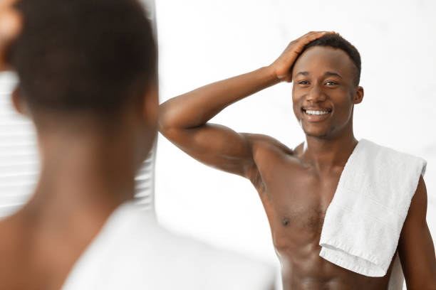 istock Black Man Touching Hair Looking In Mirror Standing In Bathroom 1281661343