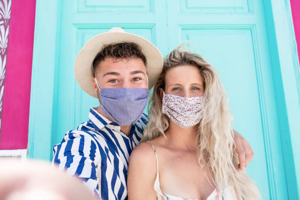 istock Cheerful caucasian couple taking a selfie while wearing protective face mask - Beautiful young people looking in camera - Concept of coronavirus lifestyle 1281661743