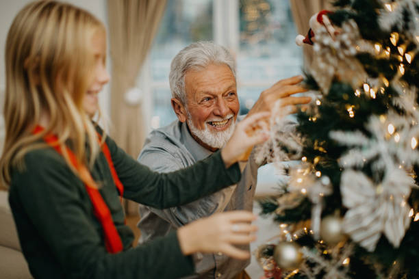istock Senior man and granddaughter decorate christmas tree 1281661914