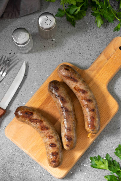 istock Grilled sausages on a wooden Board on a light gray kitchen table. View top 1281662781