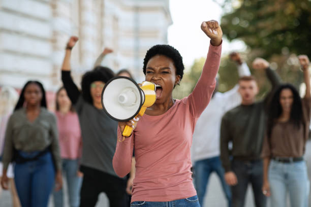 istock Black lady with megaphone leading group of demonstrators 1281663178