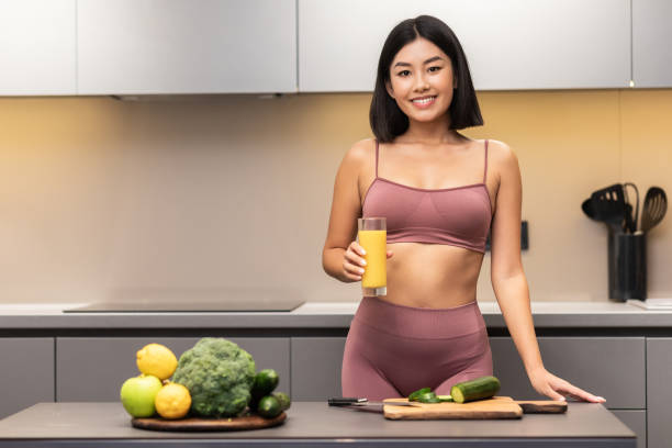 istock Cheerful Slim Japanese Woman Drinking Juice Cooking Dinner In Kitchen 1281663247
