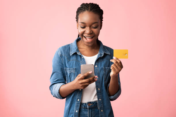African American Woman Using Smartphone And Credit Card, Pink Background Mobile Shopping App. Cheerful African American Woman With Smartphone And Credit Card Making Online Payment Standing Over Pink Studio Background. Banking Phone Application, E-Commerce Advertisement mobile payment photos stock pictures, royalty-free photos & images