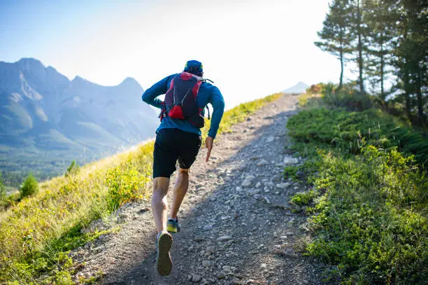 Photo of Man trail runs along mountain ridge at sunrise