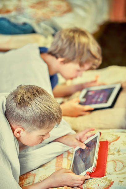 istock Gadget addiction. Two boys playing on tablets in beds 1281666362