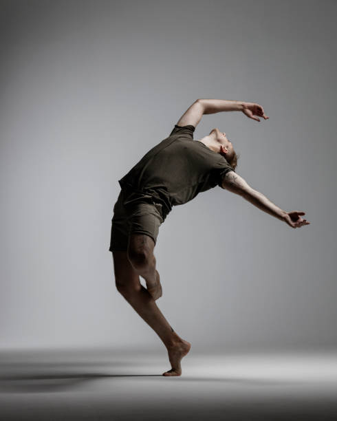 moderne männliche tänzerin auf grauem hintergrund - unterhaltungsberuf stock-fotos und bilder