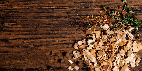 Wood chips for smoking, spices and herbs on an old wooden table top view. Free space for text.