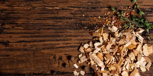 Photo of Wood chips for smoking, spices and herbs on an old wooden table