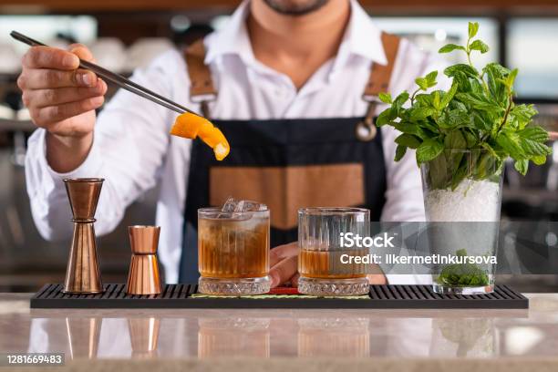 Bartender Adding Lemon Peel In A Drink Stock Photo - Download Image Now - Cocktail, Bartender, Bar - Drink Establishment