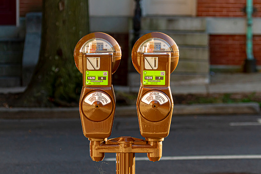 Frederick, MD, USA 10/14/2020: Close up isolated image of two  brown vintage coin operated parking meters for up to 2 hours of street parking.  It has also app compatibility for convenience.