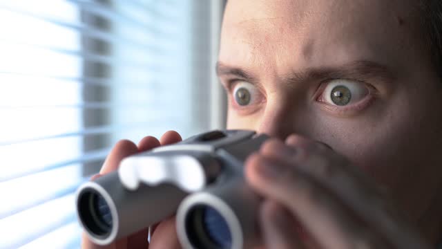 Surprised man with binoculars. Curious guy with big eyes. Nosy neighbour stalking or snooping secrets, gossip and rumour. Silly funny face. Shocked about unbelievable news.