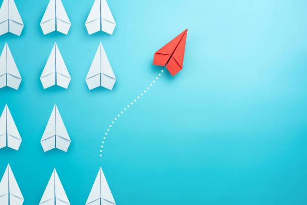 istock Group of white paper plane in one direction and one red paper plane pointing in different way on blue background. Business for innovative solution concept. 1281673207