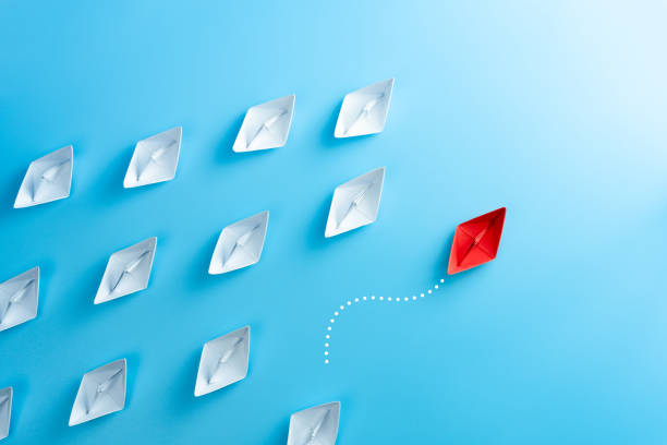 istock Red paper ship pointing in different way among white paper ship on blue background. New idea, Unique way and Business for innovative solution concept. 1281673383