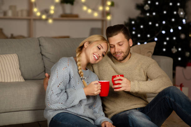 emotionales weihnachtspaar umarmt und trinkt kakao - communication discussion coffee christmas stock-fotos und bilder