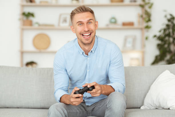 istock Excited emotional guy sitting on sofa playing video games 1281675999