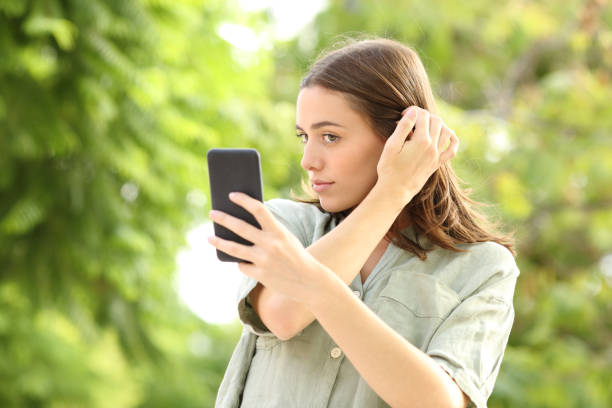 istock Woman combing using phone as a mirror in a park 1281676735