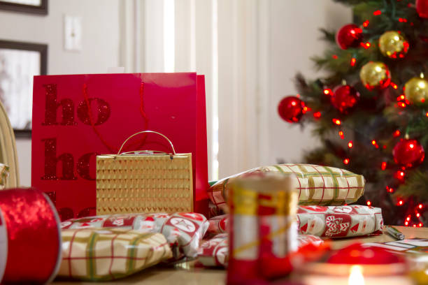 Christmas Home Latin Experience. \nElements for Christmas gift wrapping inside latin home in United States in a warm hot weather. Christmas gift wrapping papers, christmas decorations, scissors, tape and christmas bows over the dinning table.