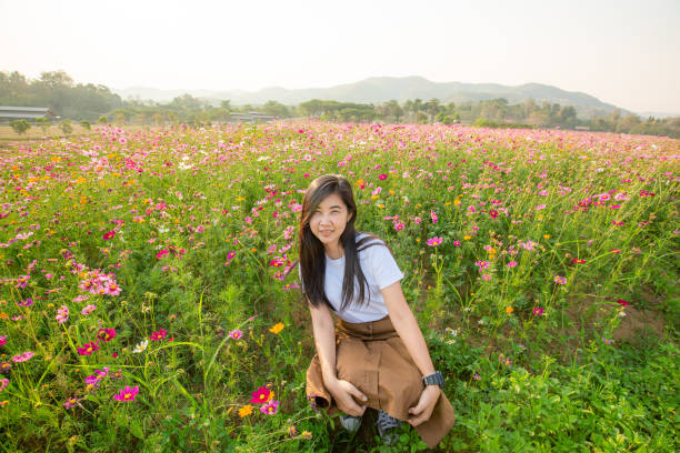 una chica con un sombrero de hilo rosa. ella está en el campo de la flor del cosmos en el fondo es el valle. - poppy oriental poppy plant spring fotografías e imágenes de stock