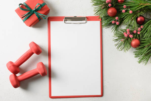 istock Christmas checklist with fir branches and gift,red dumbbells on white. Special offe. Plan training. 1281680727