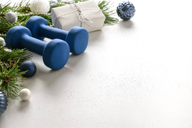 istock Christmas frame with blue dumbbells, gift, fir branches on white. Copy space. Xmas greeting card. 1281680730