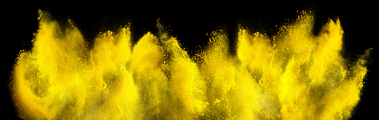 yellow holi paint color powder explosion isolated on dark black background. industry beautiful party festival concept