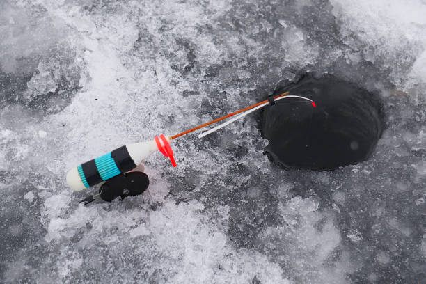 istock Winter fishing rod at drilled hole catches fish 1281684451