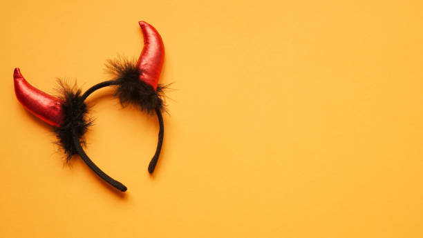 istock Red devil horns head hoop on orang background. Accessory for Halloween celebration, top view, flat lay, copy space 1281688651