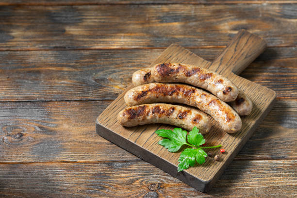 istock Grilled sausages on a wooden Board on a light gray kitchen table. 1281688867