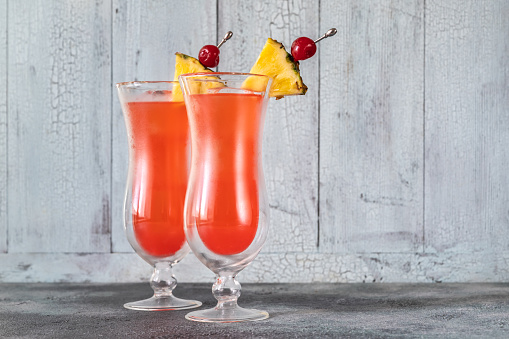 Two glasses of Singapore Sling on wooden background
