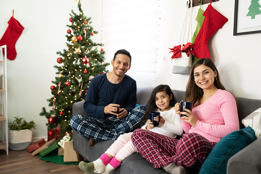 Portrait of a beautiful Latin family having a great time on Christmas while being all cozy in pajamas and drinking hot chocolate