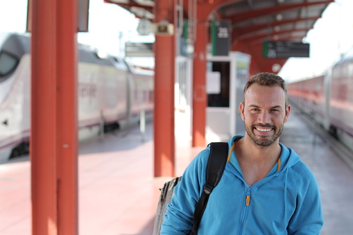 Blonde man smiling in train station.