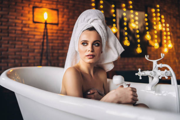 istock Woman lying in a white bath with a towel on her head. 1281690966