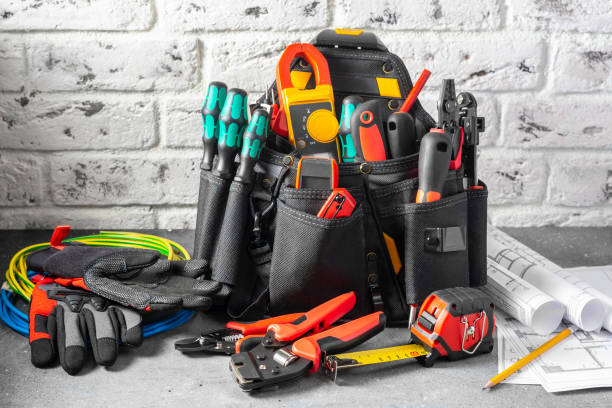 istock Electrician's tools in a black construction bag on a gray table against a white brick wall. Construction tools of an installer or electrician. Space for text 1281691192
