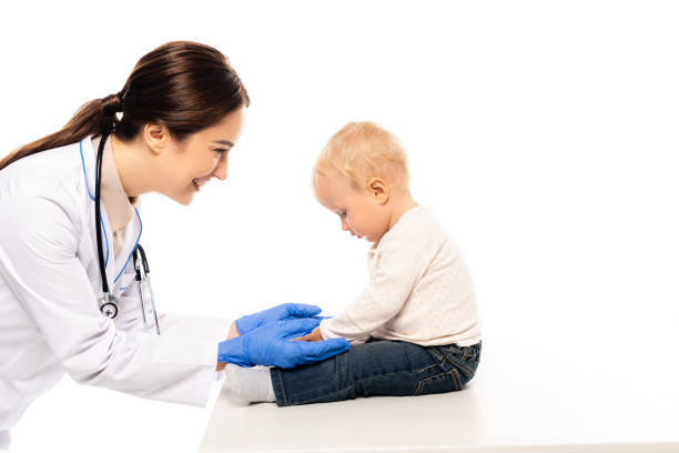 istock Smiling pediatrician touching toddler boy on table isolated on white 1281692232