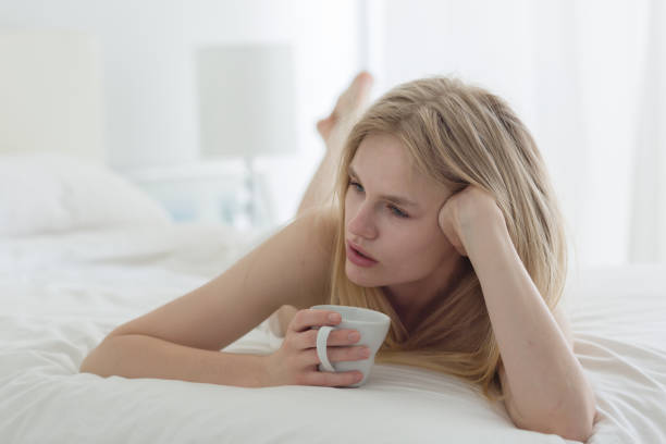 istock Pensive young woman drinking coffee in bed. 1281693494