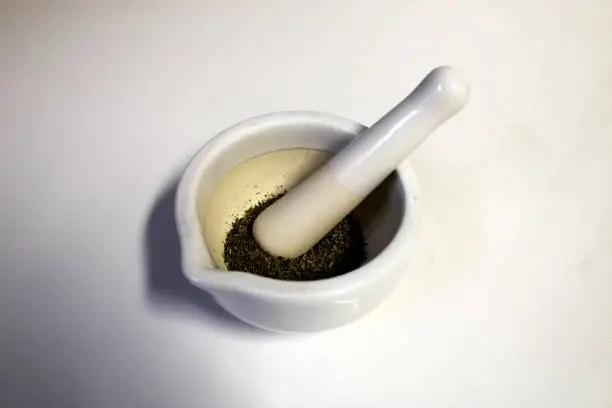My white ceramic mortar and pestle with dried ground herbs on a white background