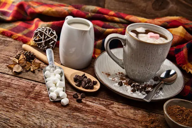 This is a photograph of hot chocolate on a wood background surrouned by ingredients