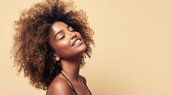 Cabello afro natural. Amplia sonrisa dentada y expresión de alegría en la cara de la joven mujer de piel marrón. Belleza afro. photo