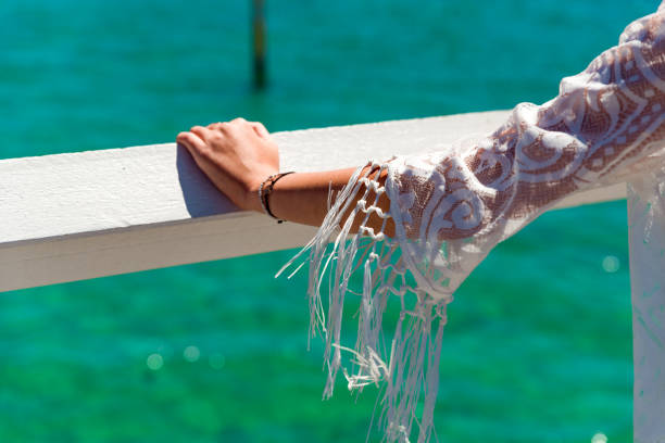 загорелая женщина рука носить браслеты. крупным планом белого кружева летний наряд - women sarong beach white стоковые фото и изображения