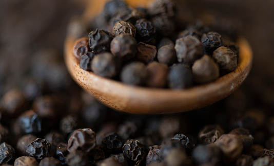 Black peppercorns and wooden spoon.