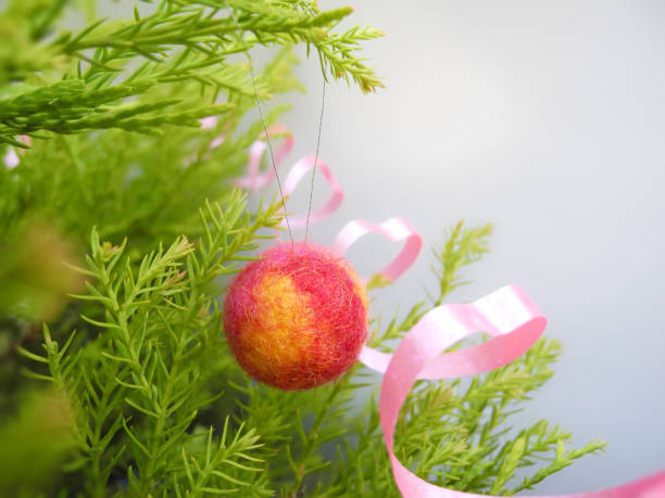 Handmade ball from natural wool on Christmas tree branches on light background stock photo